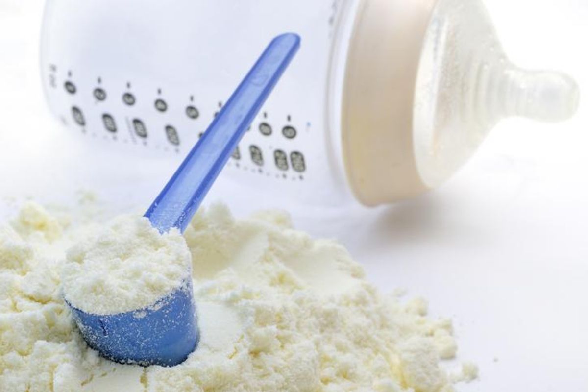 A close-up shot of baby milk formula with a plastic measuring spoon and bottle.