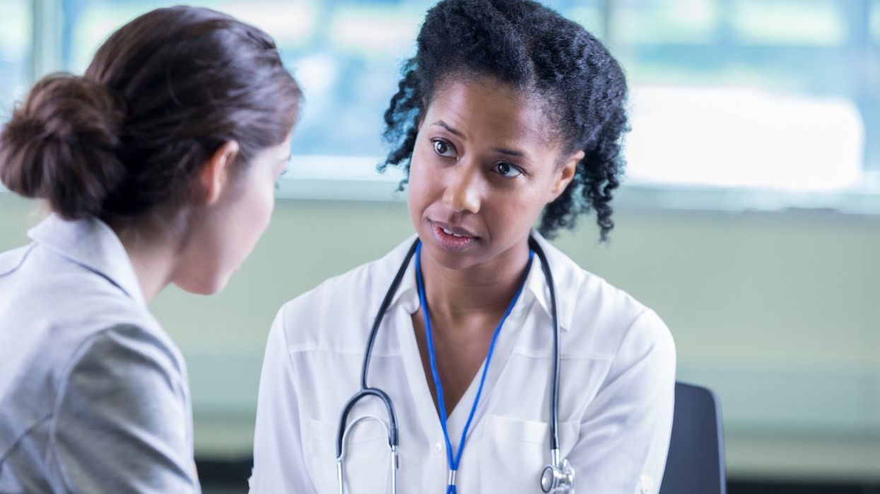 A compassionate female doctor sits across from a patient and listens to her story.