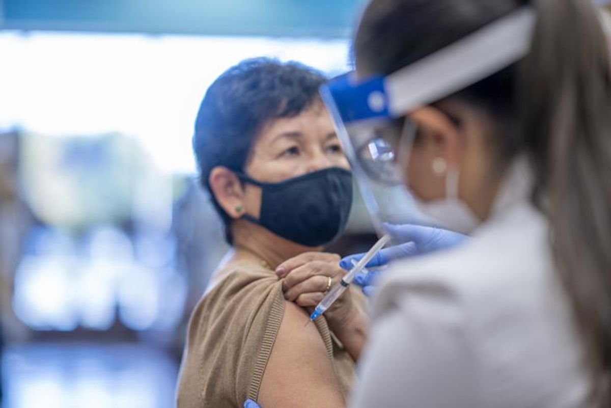A woman raises her sleeve to receive an injection from a doctor at the pharmacy.