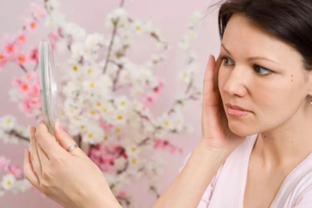 adult acne - woman looking in the mirror