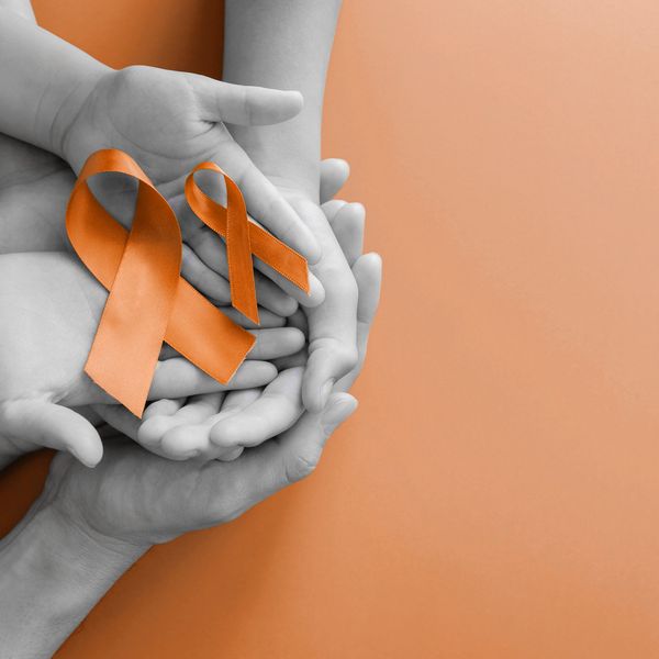 Adult and child hands holding orange Ribbons, Leukemia cancer and Multiple sclerosis awareness
