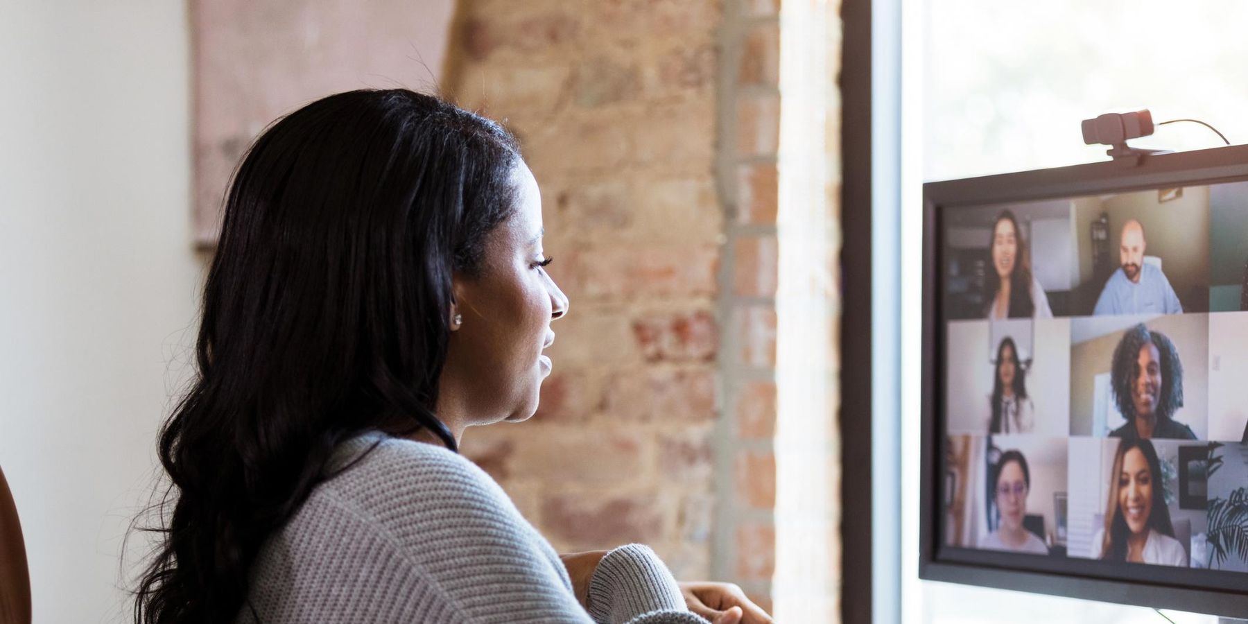 adult woman uses video conferencing to meet with her colleagues.