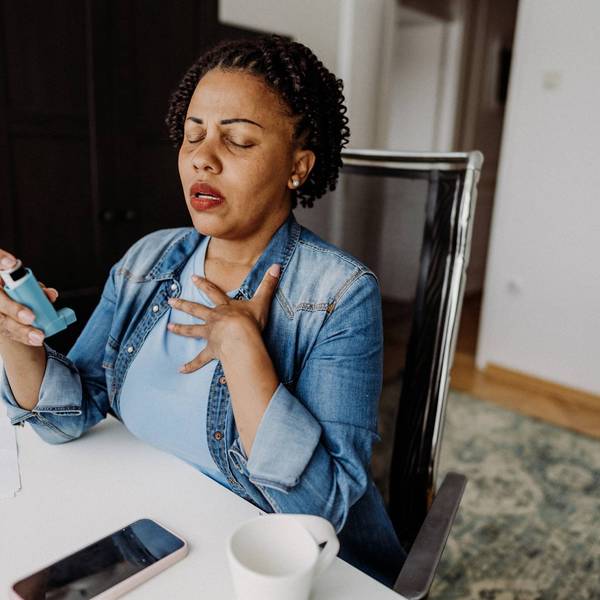 adult woman using her asthma inhaler