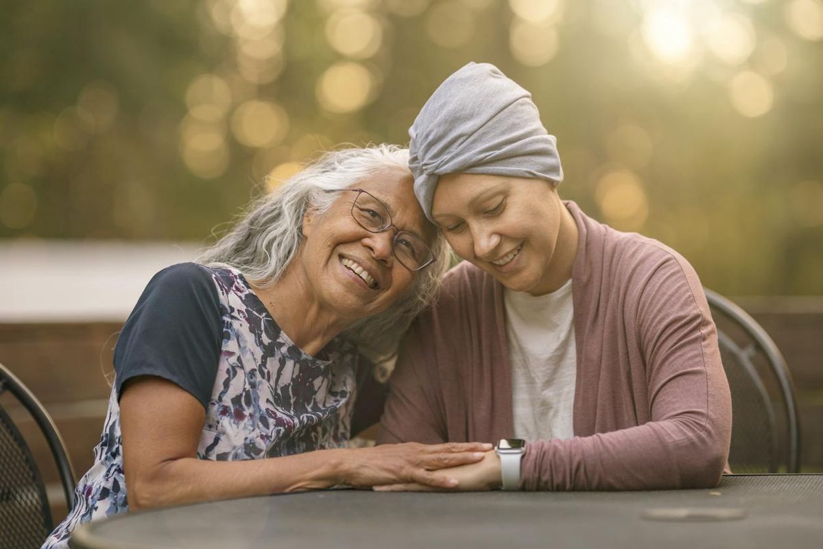 Affectionate mother embracing her adult daughter who is fighting cancer