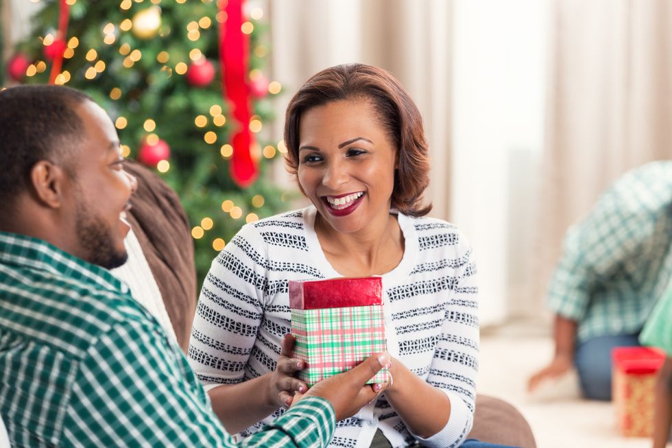 African American couple looking at each other while opening Christmas gifts