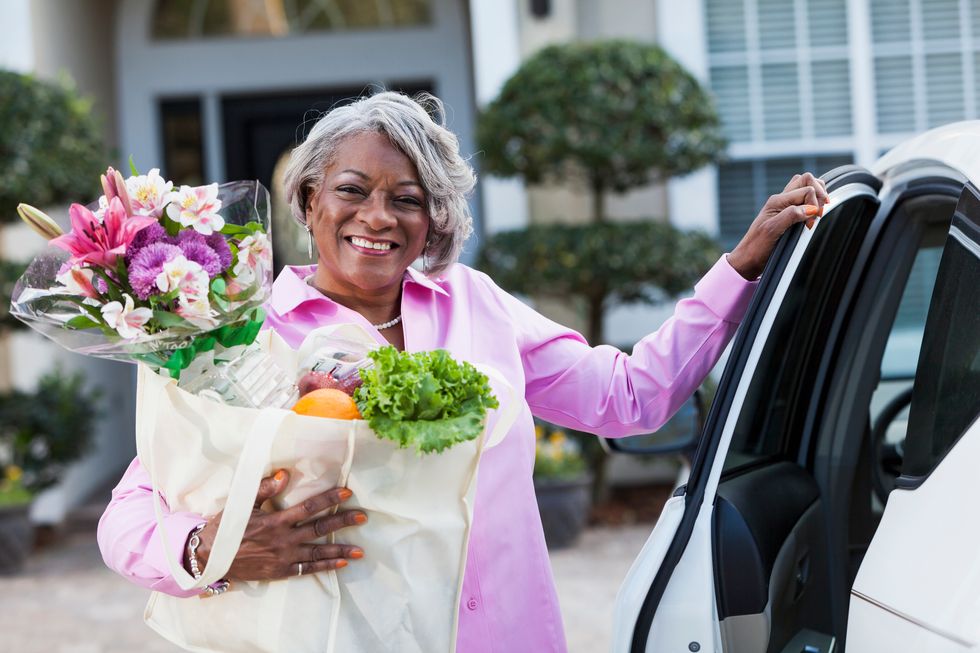 African American woman (50s) in driveway, coming home from grocery shopping