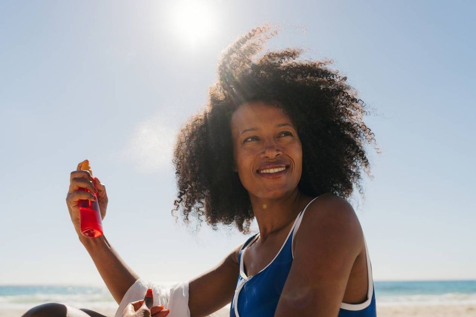 African American woman applying sunscreen spray on her hair