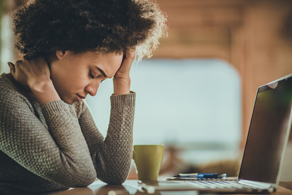 African American woman having a headache from working on a computer at home
