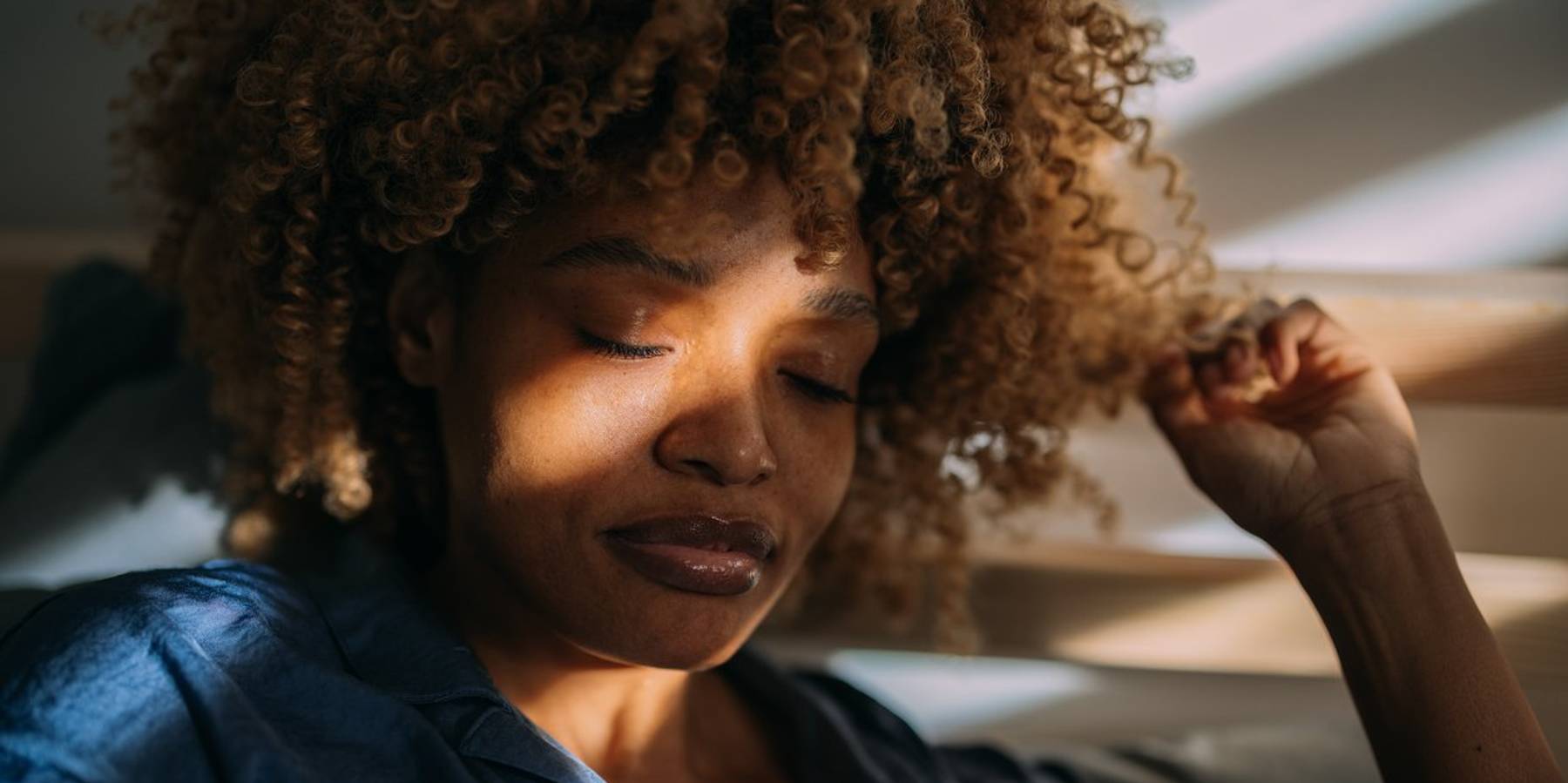 African American woman in pajamas resting in her bed at home.