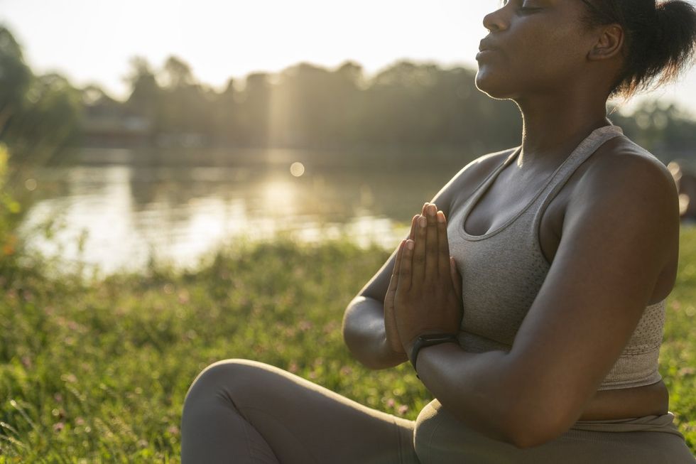 Femme afro-américaine pratiquant des exercices de respiration dans le parc
