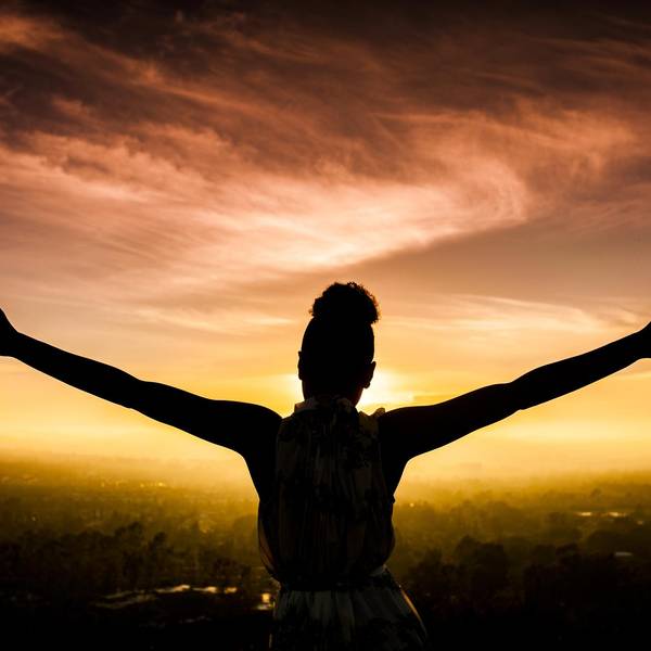 African American Woman Raising Arms at Sunset