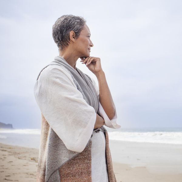 African American woman standing on the beach looking at at the ocean