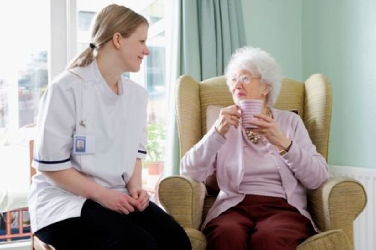 aide sitting with elderly woman