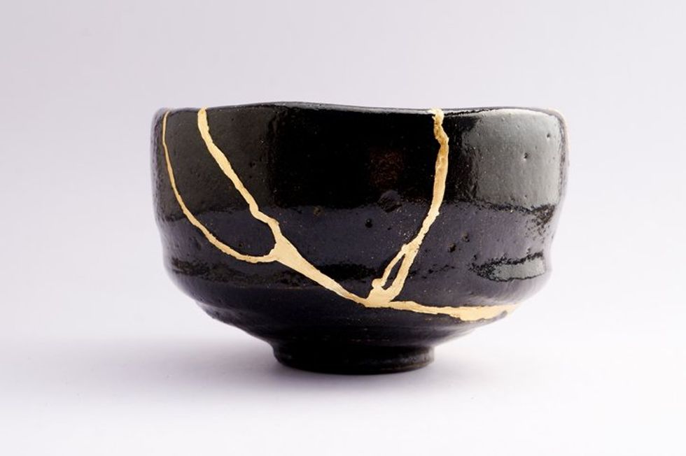 Antique broken Japanese raku black bowl repaired with gold kintsugi technique