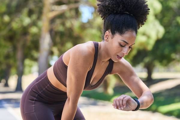 Athletic Woman On A Park Run Checks Time During Outdoor Training Session
