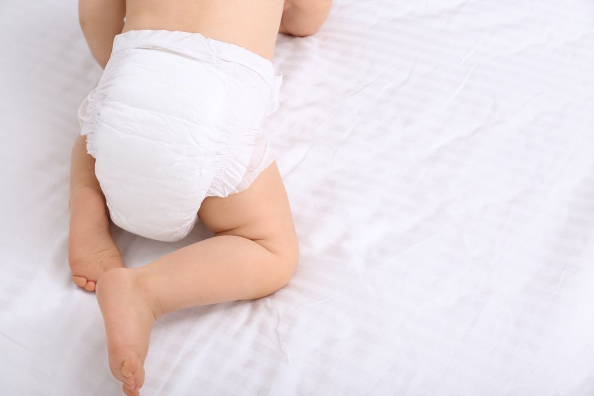 baby in dry soft diaper on white bed