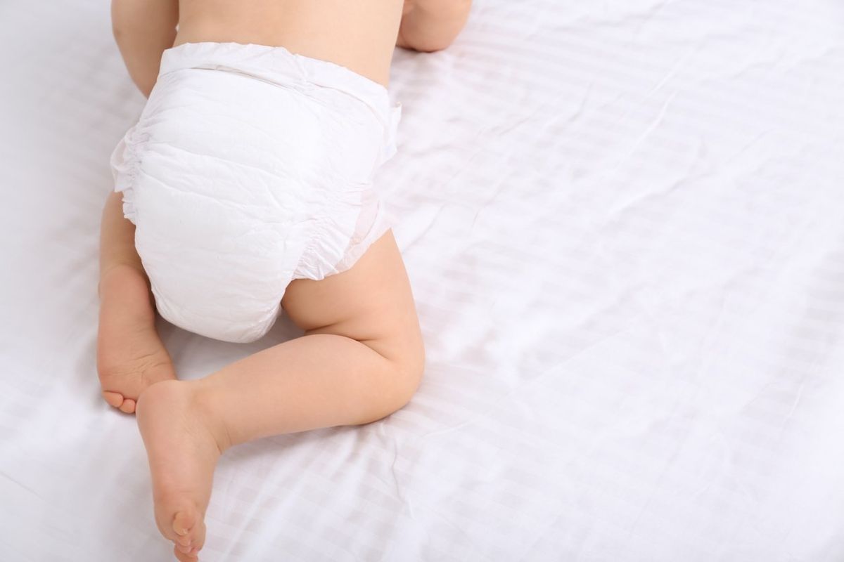baby in dry soft diaper on white bed