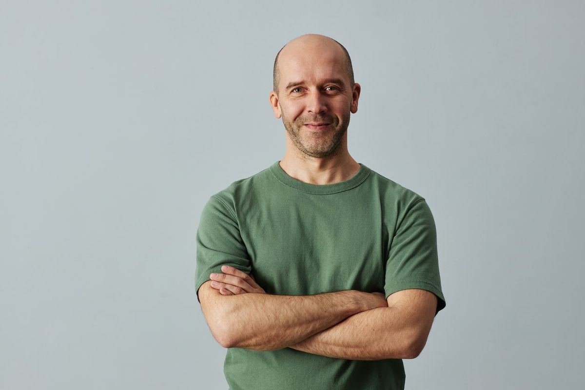 Bald man smiling at camera standing with arms crossed