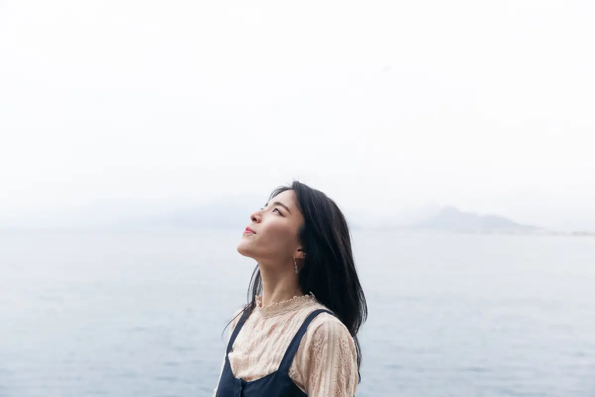 Beautiful woman standing in front of a lake looking at the sky