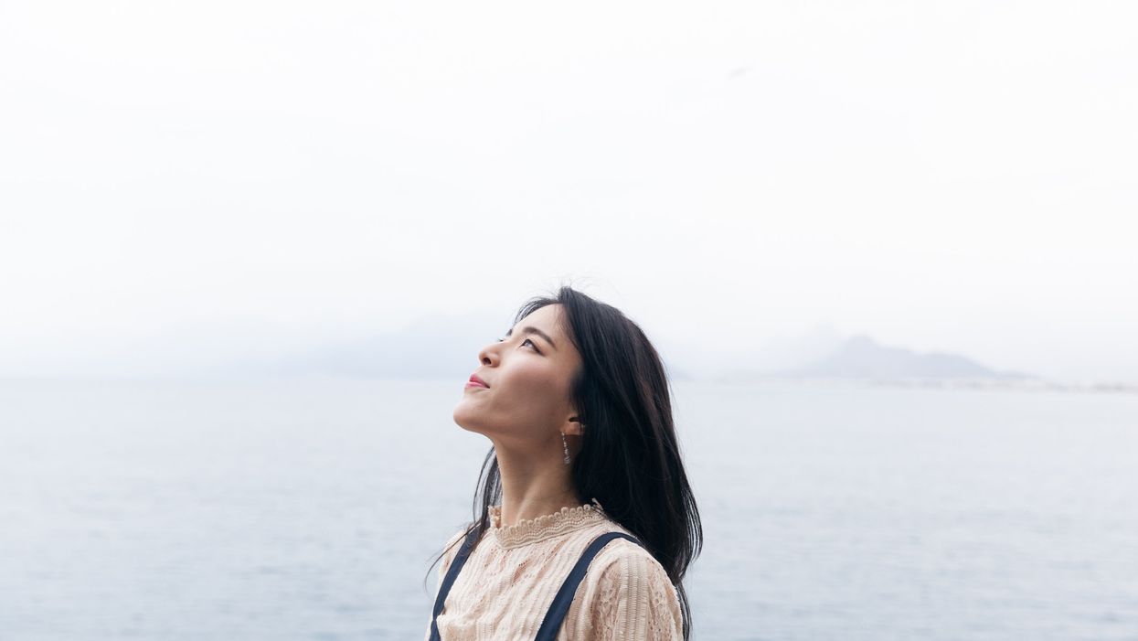 Beautiful woman standing in front of a lake looking at the sky