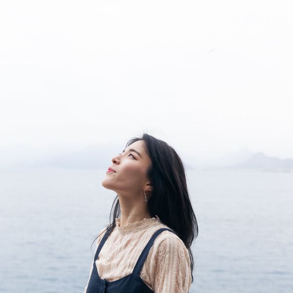 Beautiful woman standing in front of a lake looking at the sky