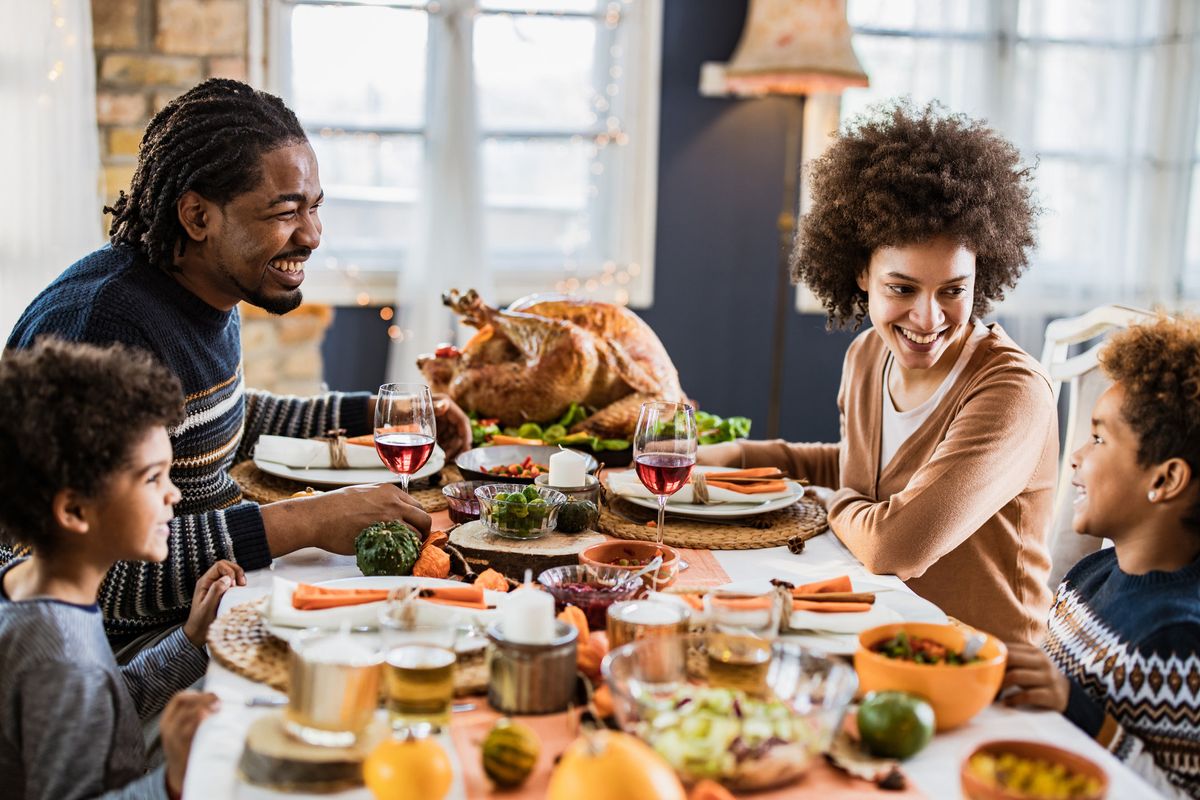 black family talking during Thanksgiving meal at dining table