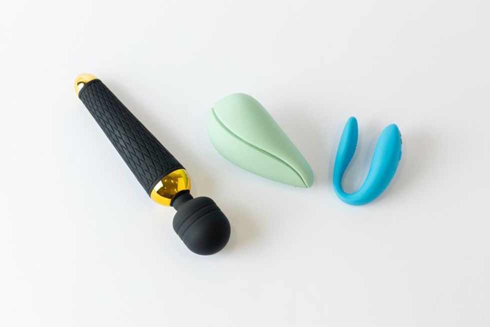 black large vibrator in the shape of a microphone next to it lie a vacuum mint and with double penetration blue vibrators various sex toys