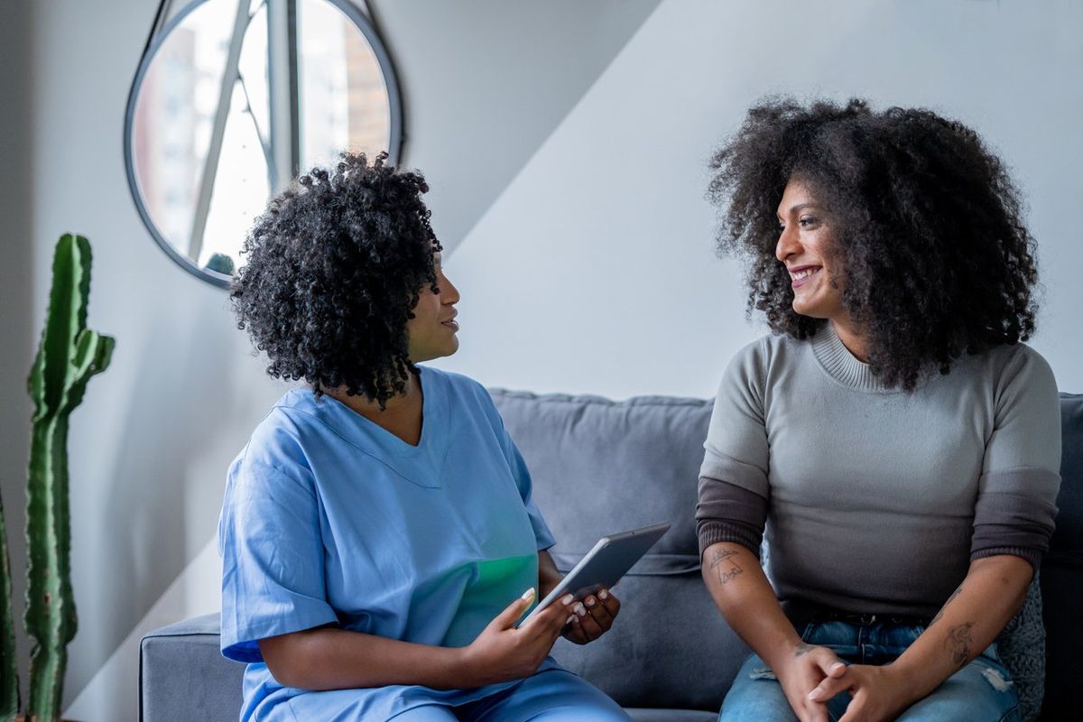 Black nurse consulting trans woman at home