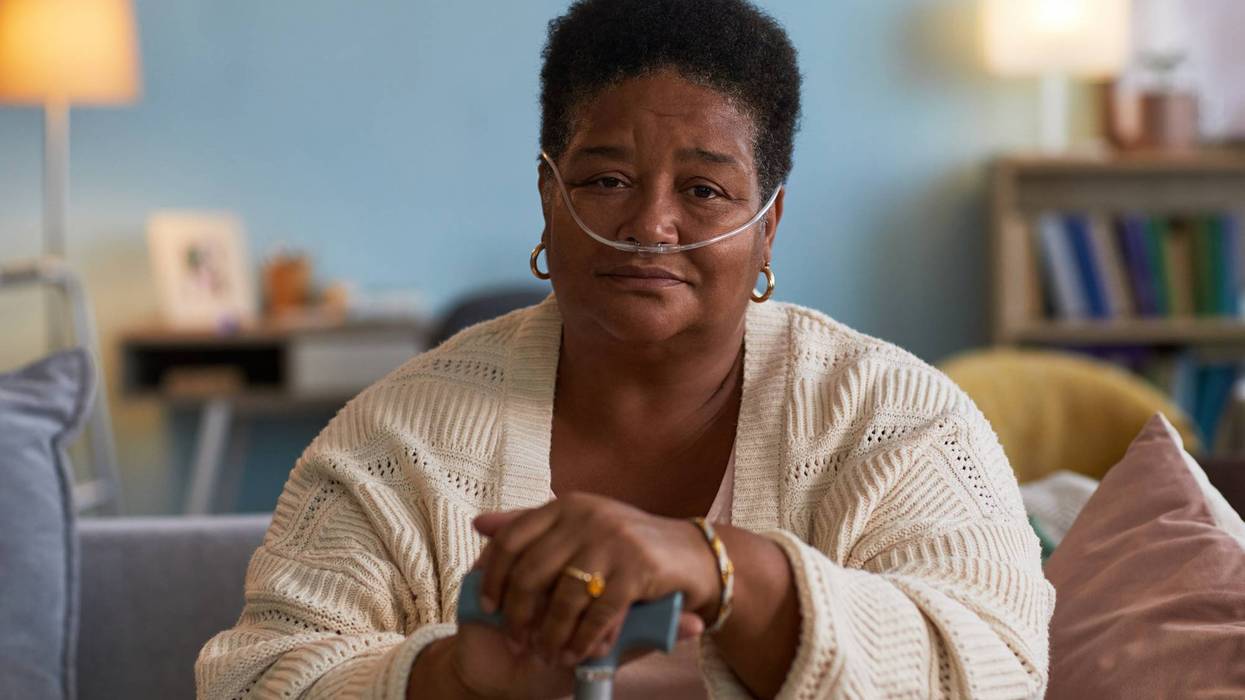 Black woman with copd sitting indoors using oxygen tube