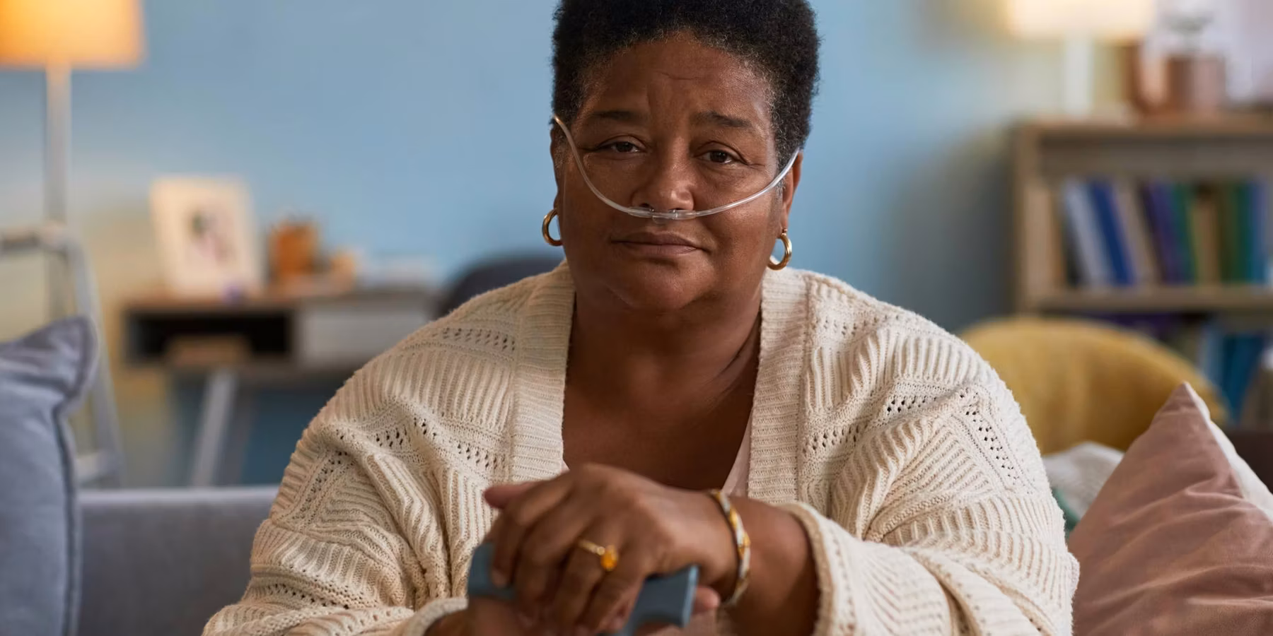 Black woman with copd sitting indoors using oxygen tube