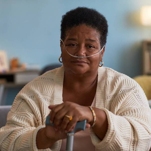 Black woman with copd sitting indoors using oxygen tube