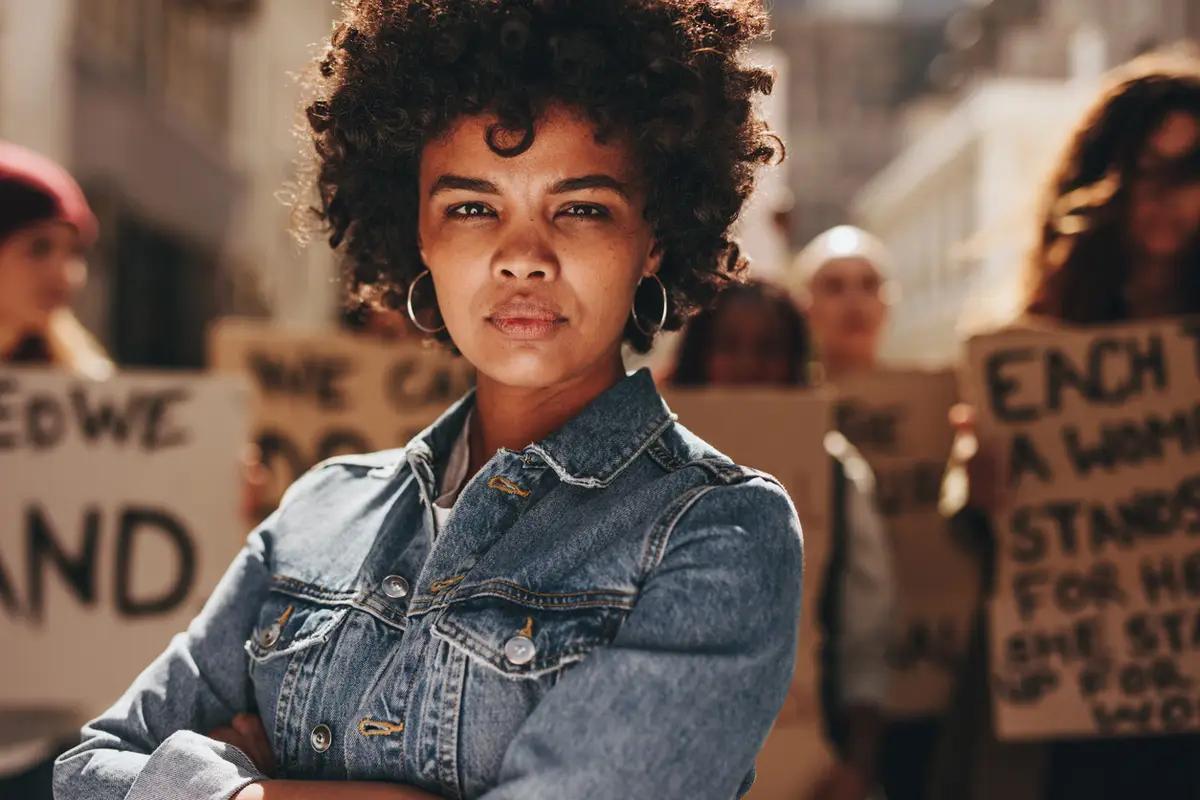 black woman with group of demonstrator in background outdoors