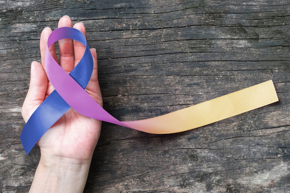 Bladder cancer awareness marigold blue purple ribbon on helping hand support