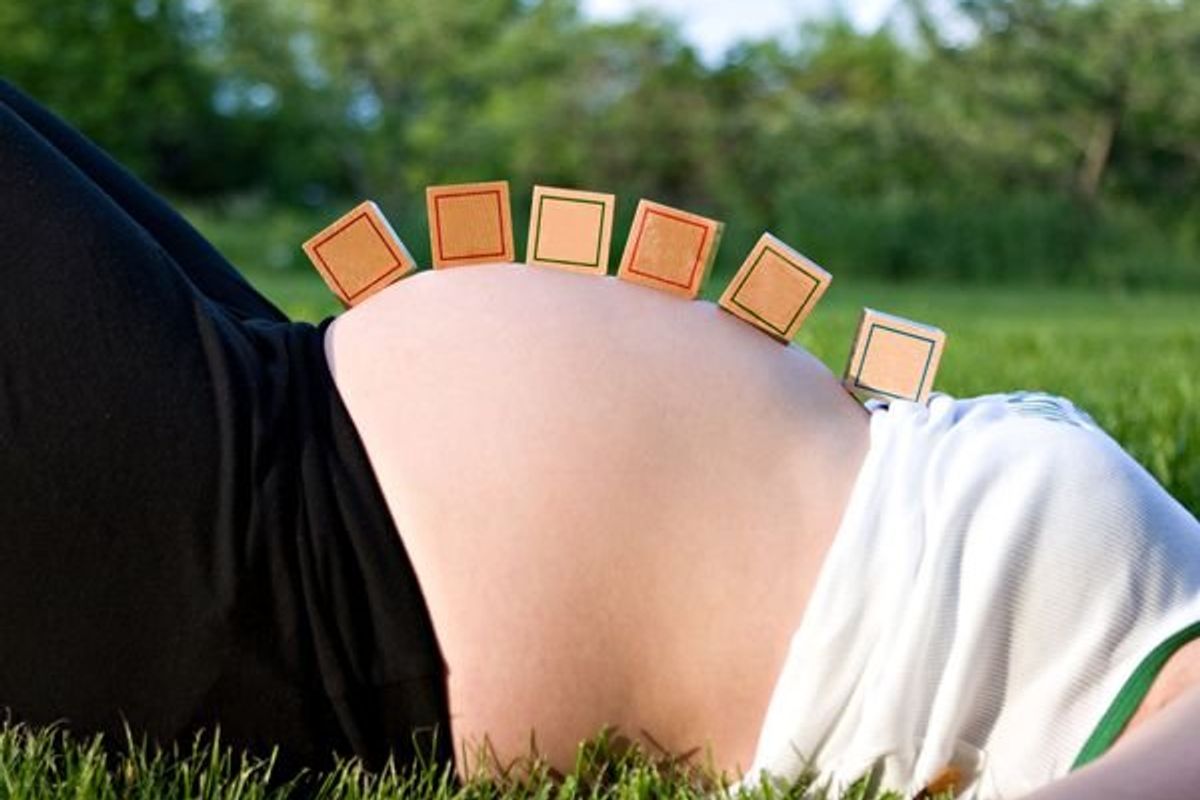 blank baby blocks resting on pregnant mother's stomach