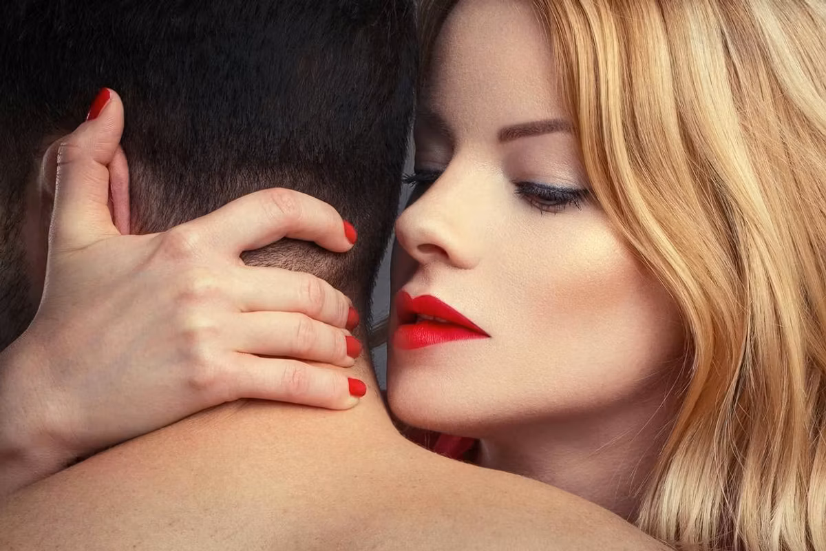 blonde woman in red lips holding man in arms at night