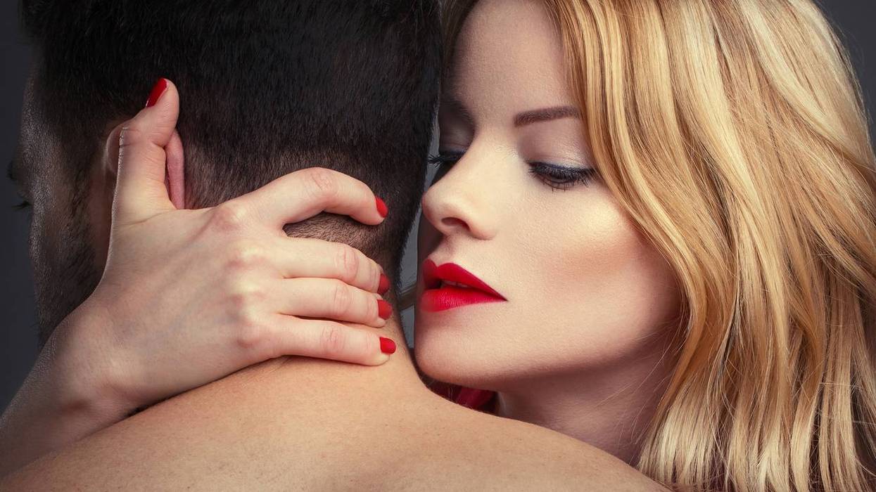 blonde woman in red lips holding man in arms at night