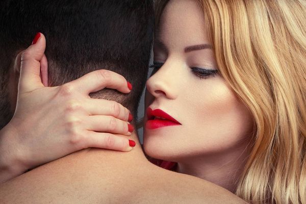 blonde woman in red lips holding man in arms at night