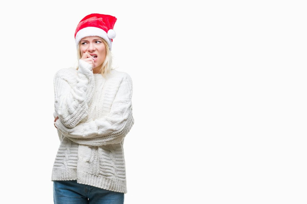 blonde woman wearing christmas hat over isolated background looking stressed and nervous with hands on mouth biting nails