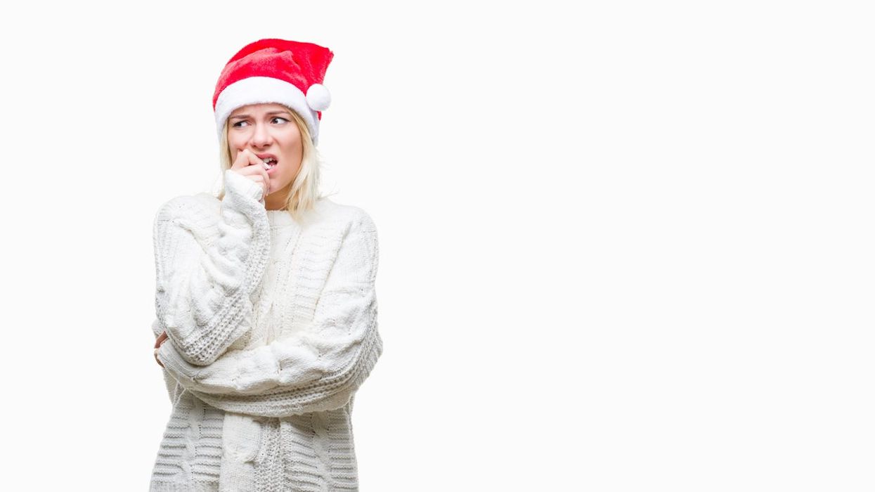 blonde woman wearing christmas hat over isolated background looking stressed and nervous with hands on mouth biting nails