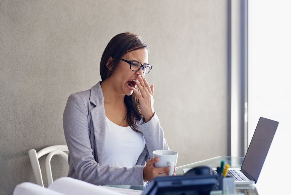 businesswoman yawning while sitting at her desk