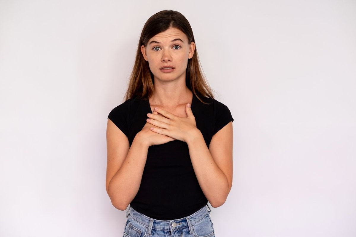 Caucasian lady wearing black T-shirt and jeans looking at camera and touching chest