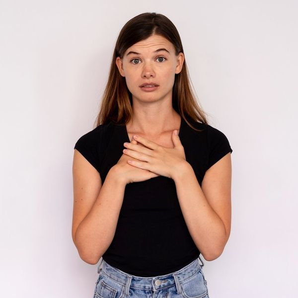 Caucasian lady wearing black T-shirt and jeans looking at camera and touching chest