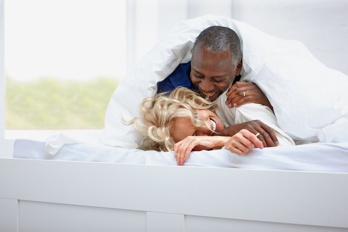 Cheerful mature couple spending time together on bed