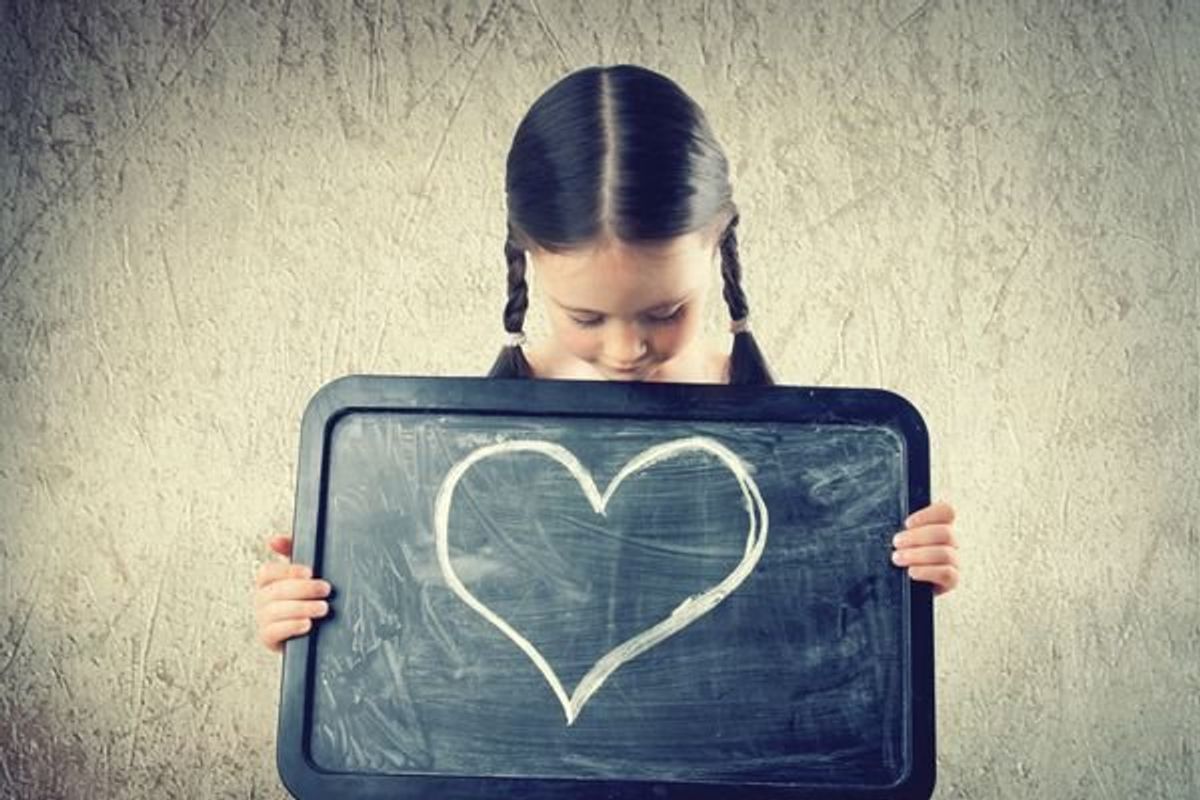 child holding a chalk drawing of a heart