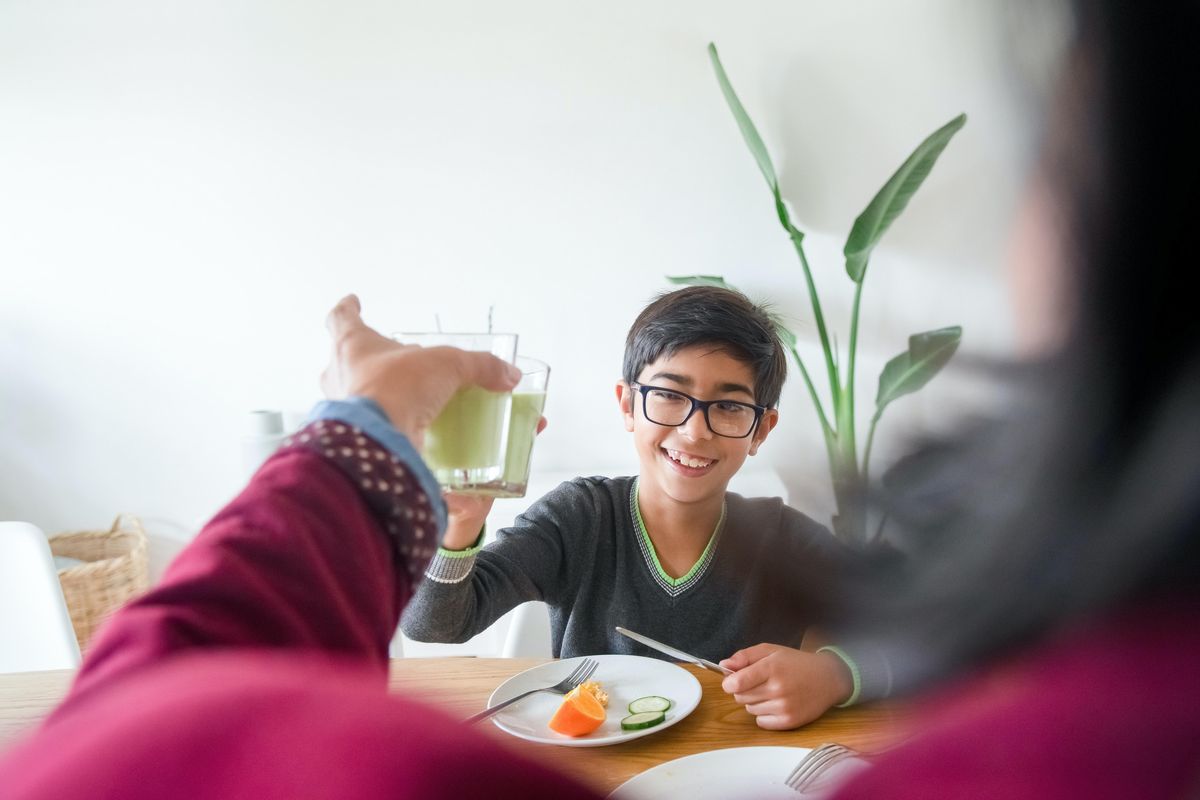 child raising a glass of green juice