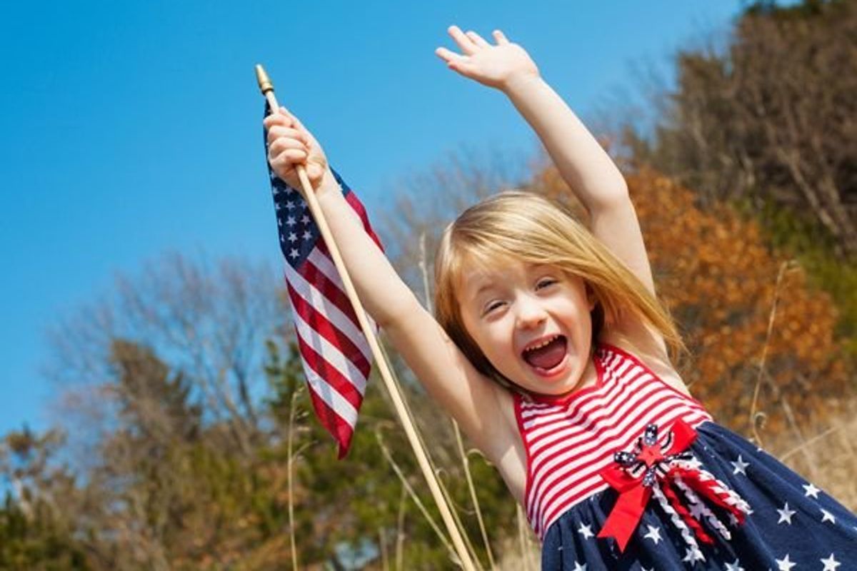 child wearing july 4th dress and holding a flag