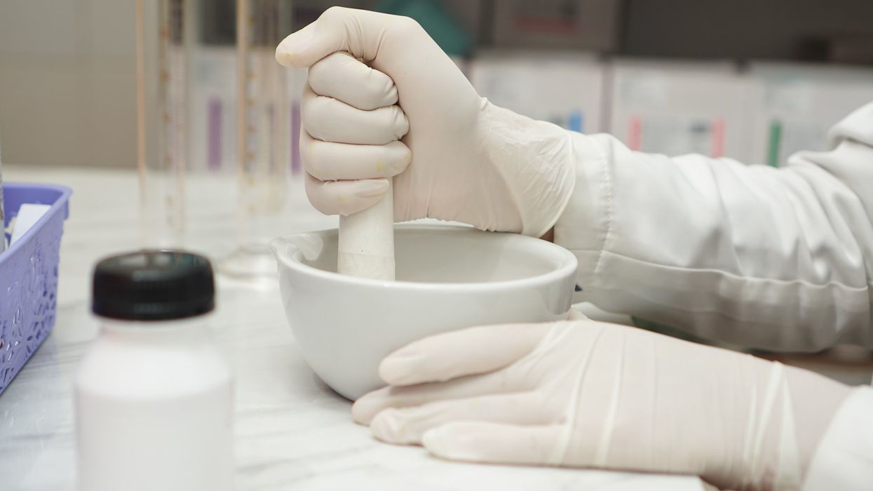close up of pharmacists mixture a medicine with a mortar and using glove
