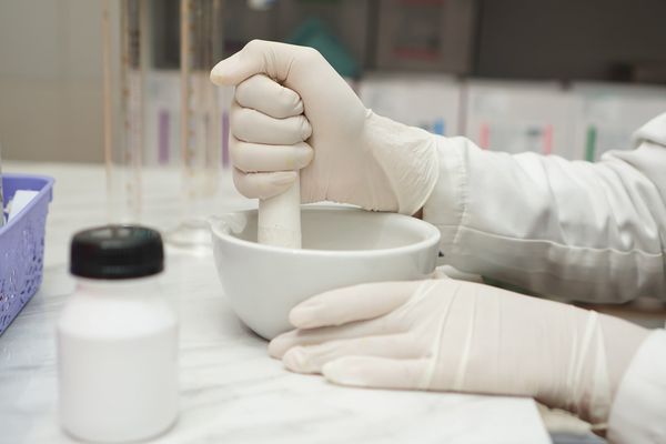 close up of pharmacists mixture a medicine with a mortar and using glove