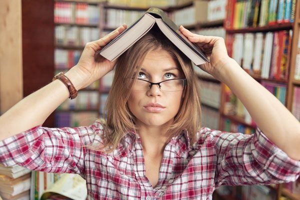 college woman holding a book on her head