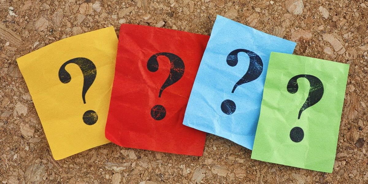 Colorful paper notes with question marks on a cork board